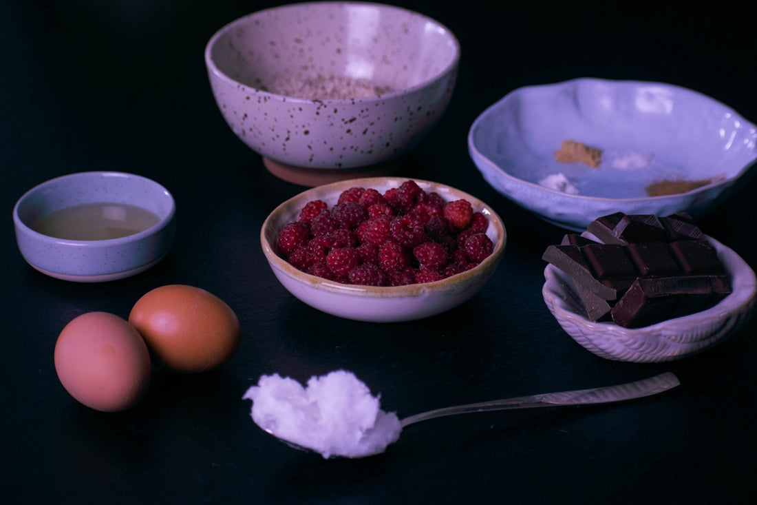 Assorted baking ingredients: raspberries, chocolate, eggs, oats, and oil.
